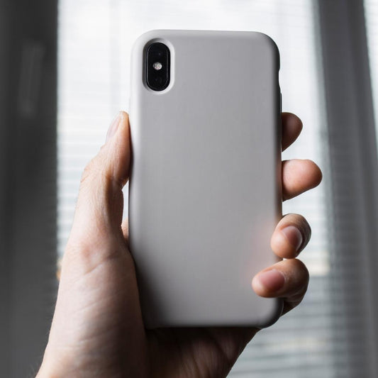 iphone x with gray case in hand